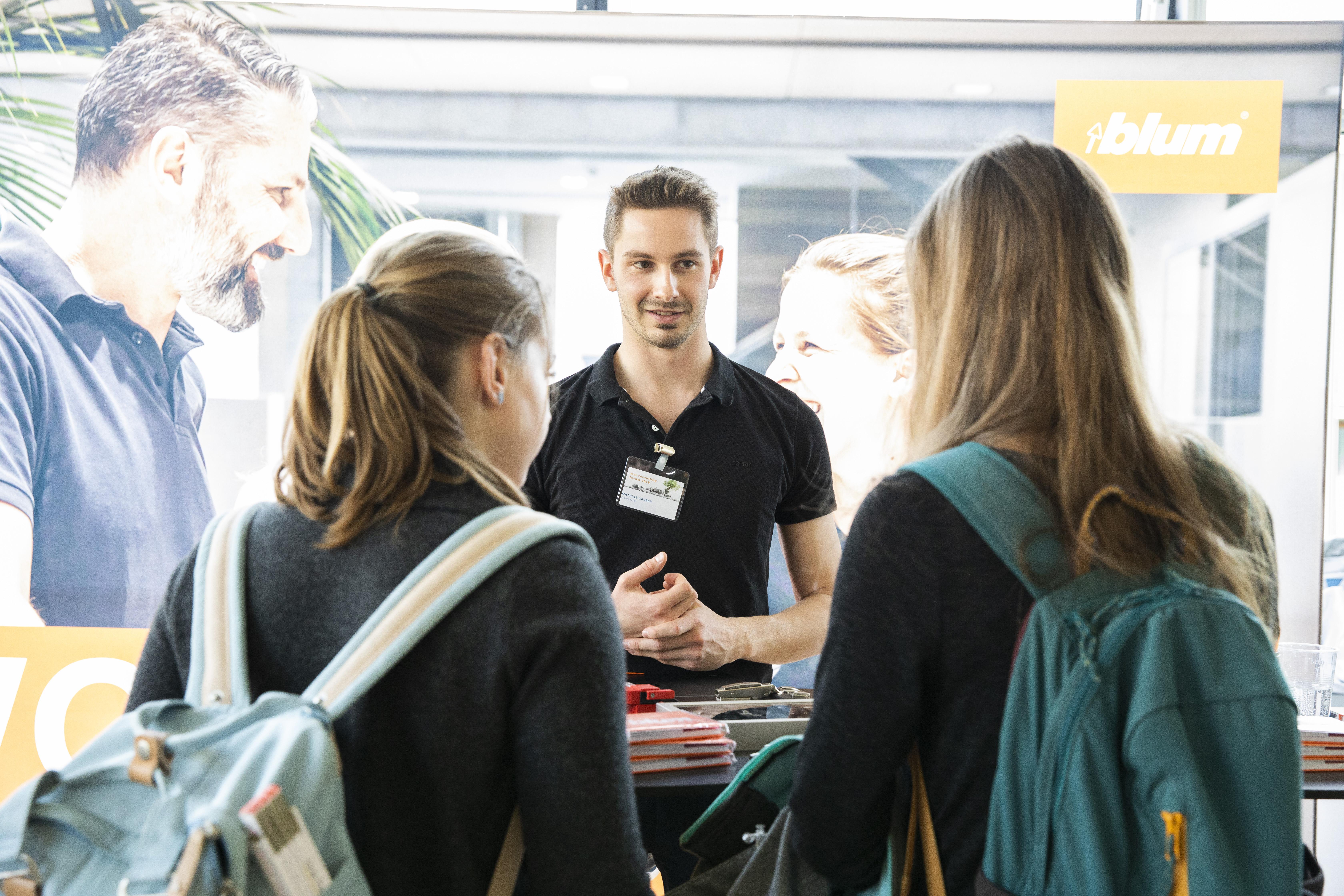 Zwei Studentinnen reden mit einem Mitarbeiter von Blum